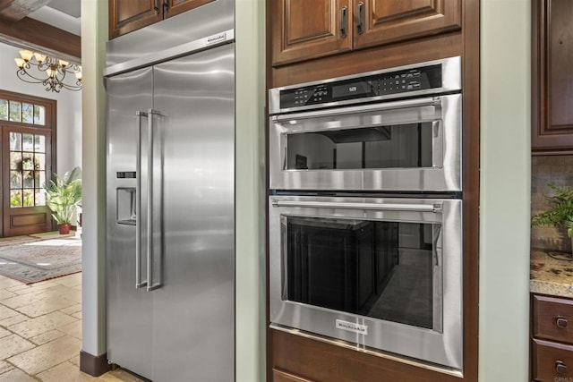 kitchen featuring light stone countertops, a notable chandelier, and stainless steel appliances