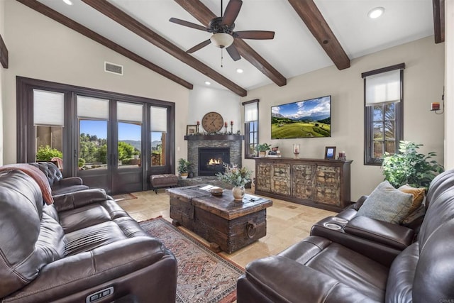 living room with vaulted ceiling with beams, a stone fireplace, a wealth of natural light, and ceiling fan