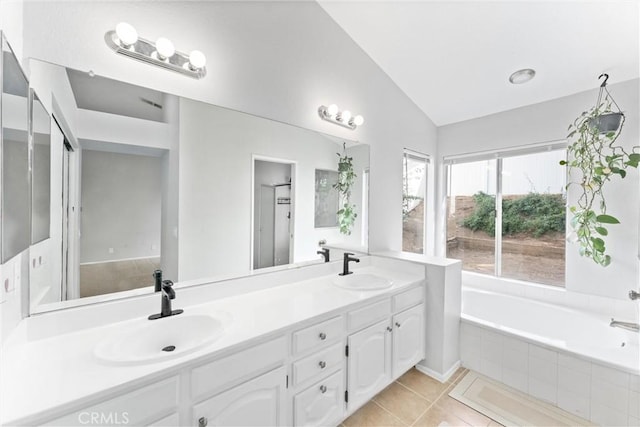 bathroom featuring a relaxing tiled tub, vanity, tile patterned flooring, and vaulted ceiling