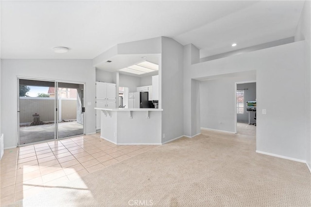 unfurnished living room featuring lofted ceiling and light tile patterned flooring