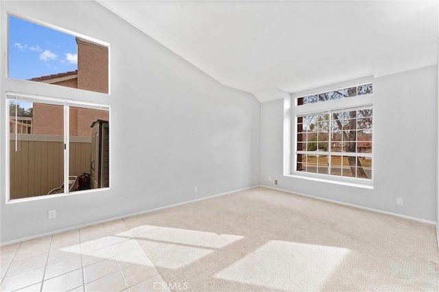 empty room with vaulted ceiling and light tile patterned flooring