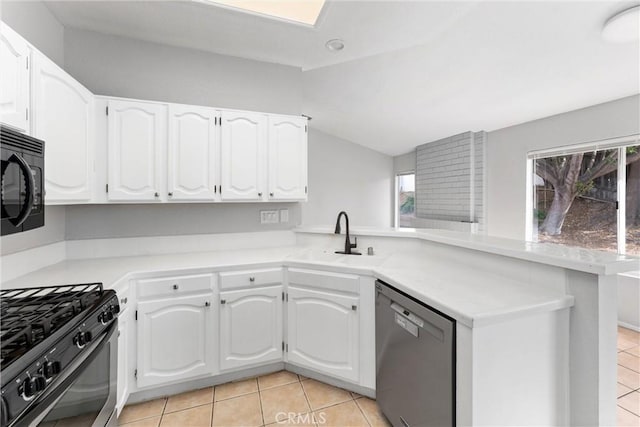 kitchen with vaulted ceiling, kitchen peninsula, sink, white cabinets, and black appliances