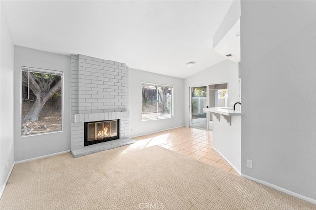 unfurnished living room featuring lofted ceiling, light carpet, and a brick fireplace