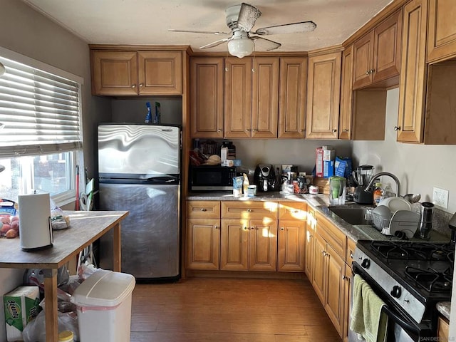 kitchen with appliances with stainless steel finishes, sink, dark wood-type flooring, and ceiling fan