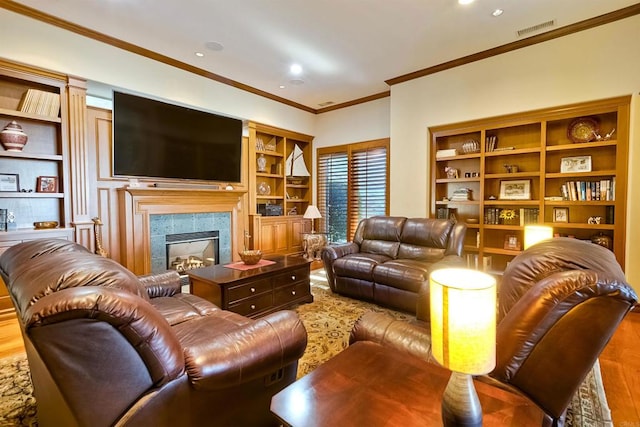 living room featuring a tiled fireplace, hardwood / wood-style floors, crown molding, and built in features