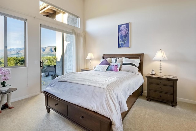 bedroom with light colored carpet, a mountain view, and access to outside