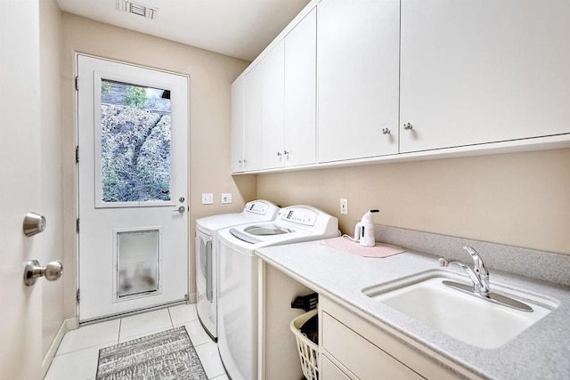 clothes washing area with light tile patterned flooring, cabinets, separate washer and dryer, and sink