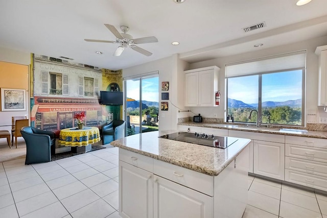 kitchen with white cabinetry, sink, light tile patterned floors, light stone counters, and black electric cooktop