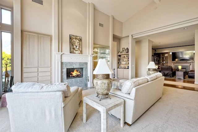 living room with built in shelves, high vaulted ceiling, and a premium fireplace