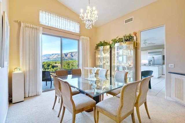 dining room featuring a mountain view, vaulted ceiling, light carpet, and a notable chandelier