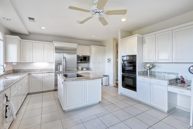 kitchen featuring sink, light stone counters, black appliances, white cabinets, and a kitchen island