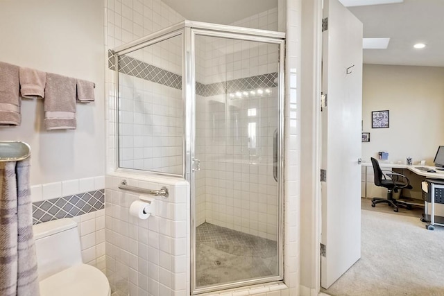 bathroom with toilet, a shower with door, and tile walls