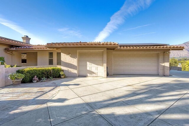 15615 Pauma Valley Dr, Pauma Valley, CA 92061 - mediterranean / spanish-style house featuring stucco siding, an attached garage, driveway, a tiled roof, and roof mounted solar panels