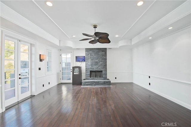 unfurnished living room featuring french doors, dark hardwood / wood-style flooring, a raised ceiling, and a stone fireplace