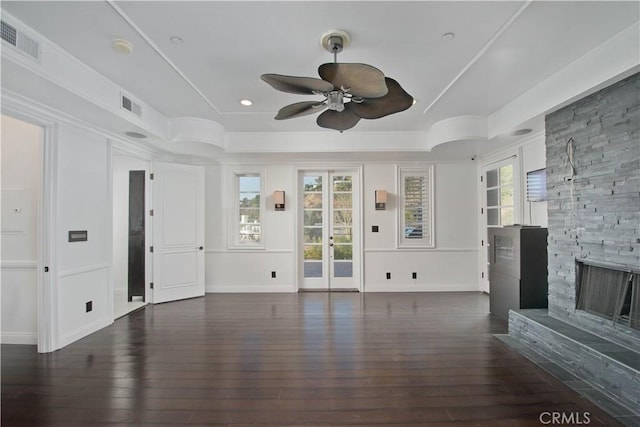 unfurnished living room with french doors, dark hardwood / wood-style floors, a tray ceiling, ceiling fan, and a fireplace