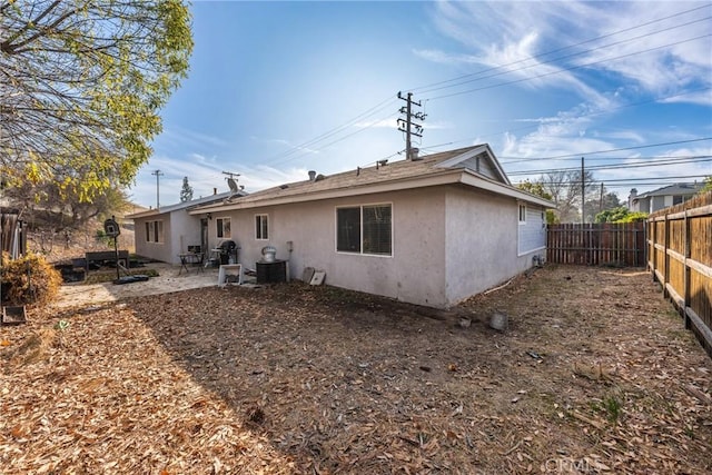 back of property with central AC unit and a patio