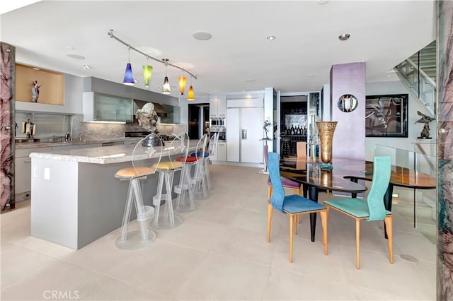 kitchen featuring paneled built in refrigerator, pendant lighting, a large island, decorative backsplash, and white cabinets