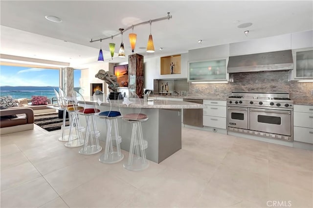 kitchen featuring stainless steel appliances, exhaust hood, white cabinets, and a water view