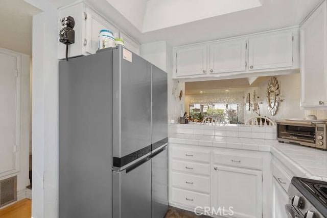 kitchen featuring white cabinetry, appliances with stainless steel finishes, and tile counters