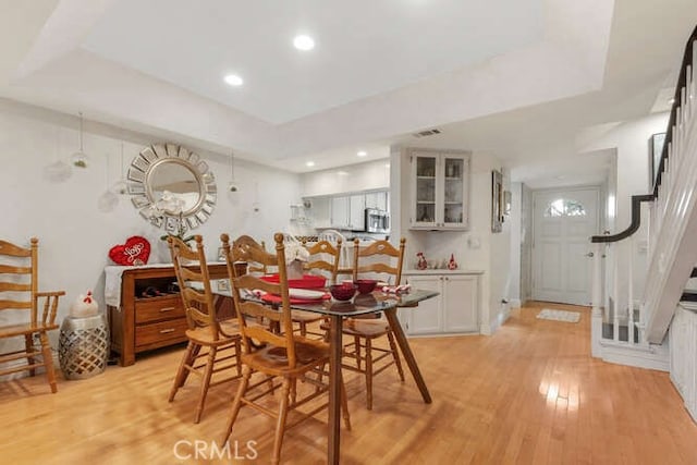 dining area featuring a raised ceiling and light wood-type flooring