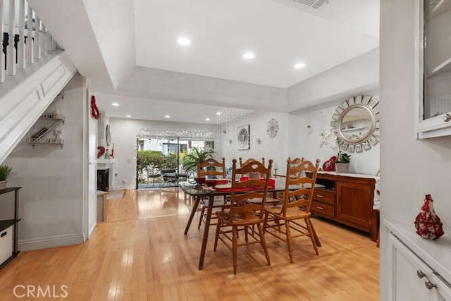 dining room with light hardwood / wood-style flooring and a raised ceiling