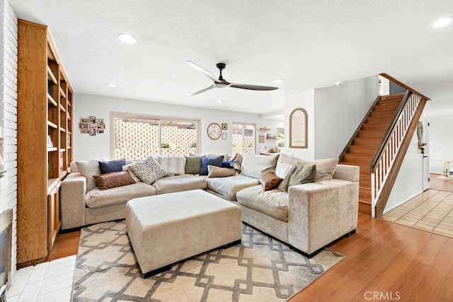 living room featuring ceiling fan, light hardwood / wood-style floors, and a textured ceiling