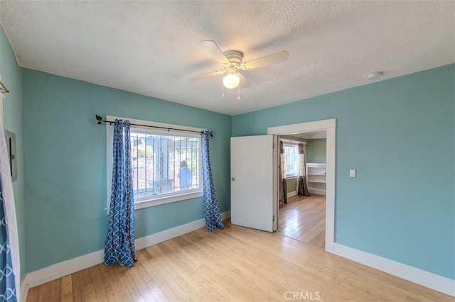 unfurnished bedroom featuring ceiling fan, light hardwood / wood-style floors, and a textured ceiling