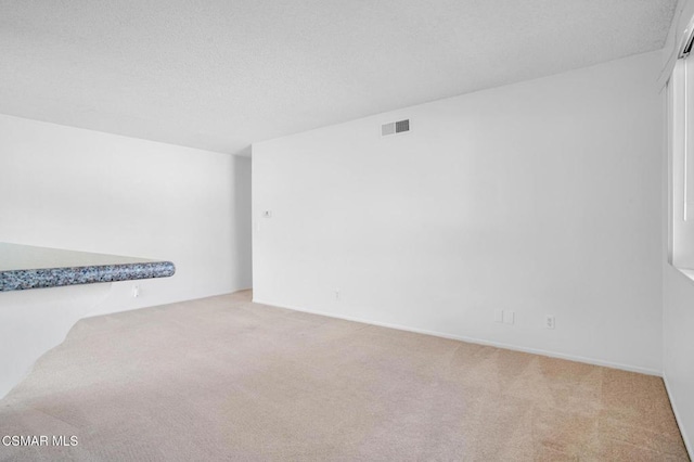 empty room with light carpet and a textured ceiling