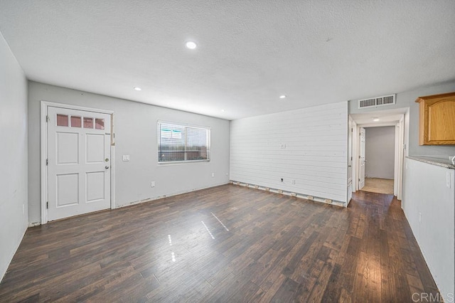 unfurnished living room featuring a textured ceiling, wood finished floors, visible vents, and recessed lighting