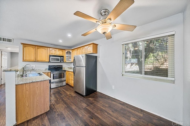 kitchen with light stone counters, stainless steel appliances, a sink, visible vents, and glass insert cabinets