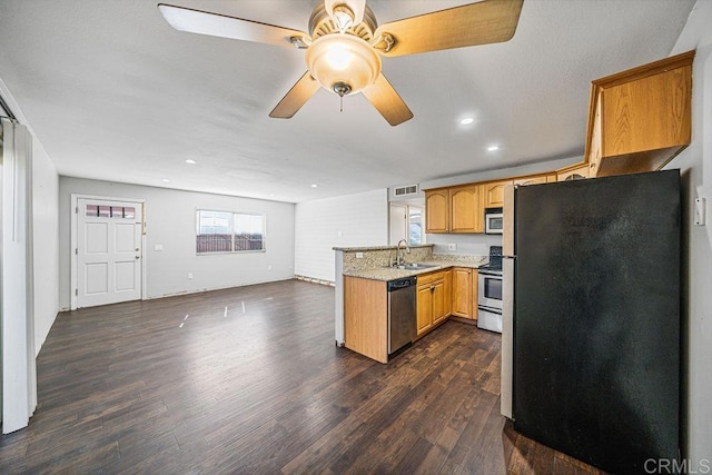 kitchen featuring visible vents, dark wood finished floors, appliances with stainless steel finishes, a peninsula, and a sink