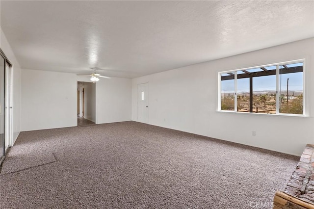 carpeted spare room featuring ceiling fan and a textured ceiling