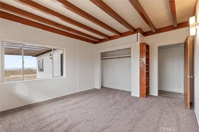 unfurnished bedroom featuring beam ceiling, a closet, and carpet flooring