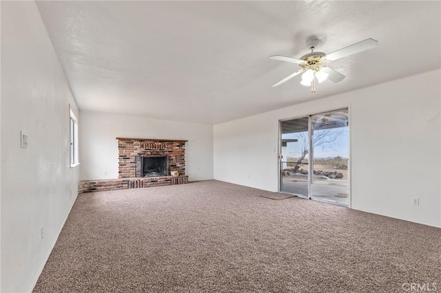 unfurnished living room featuring ceiling fan, a healthy amount of sunlight, a fireplace, and carpet