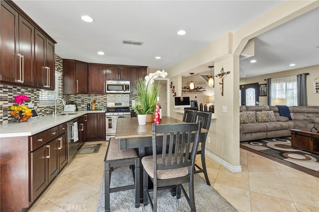 kitchen with a breakfast bar, sink, light tile patterned floors, stainless steel appliances, and backsplash