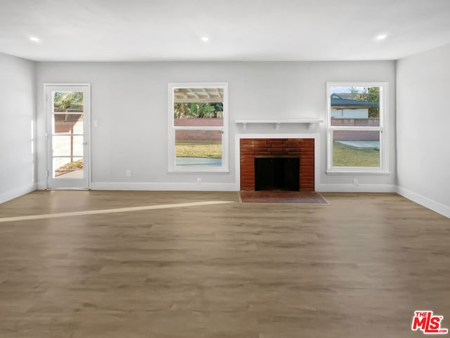 unfurnished living room with hardwood / wood-style floors and a brick fireplace