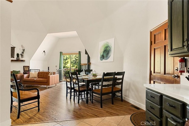 dining room featuring a towering ceiling and light wood-type flooring