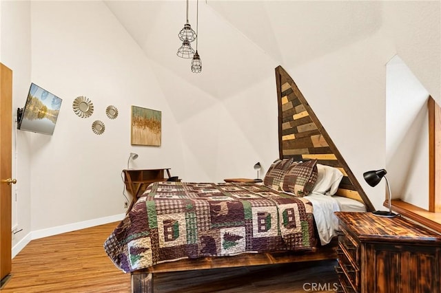 bedroom featuring high vaulted ceiling and light hardwood / wood-style flooring