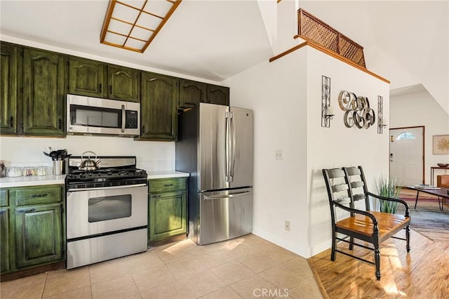 kitchen with stainless steel appliances, light tile patterned flooring, and vaulted ceiling