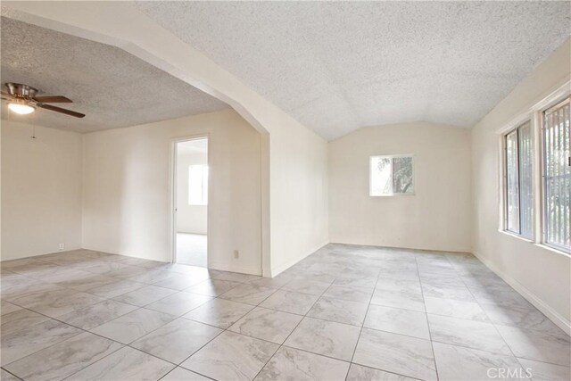 unfurnished room with ceiling fan, vaulted ceiling, and a textured ceiling