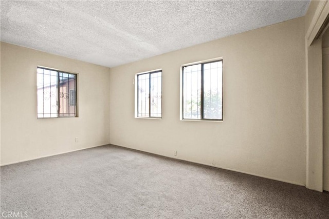 unfurnished room with carpet and a textured ceiling