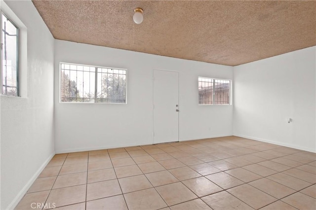 spare room with light tile patterned floors and a textured ceiling