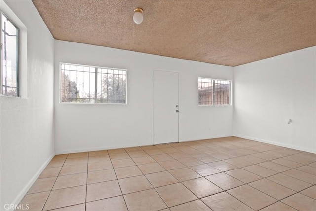 unfurnished room with a textured ceiling and light tile patterned floors