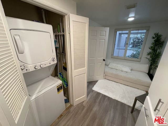 washroom featuring dark wood-type flooring and stacked washer / dryer