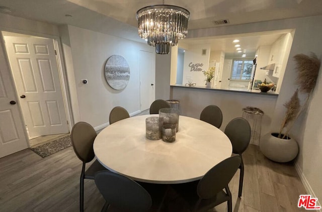 dining area with hardwood / wood-style floors and a notable chandelier