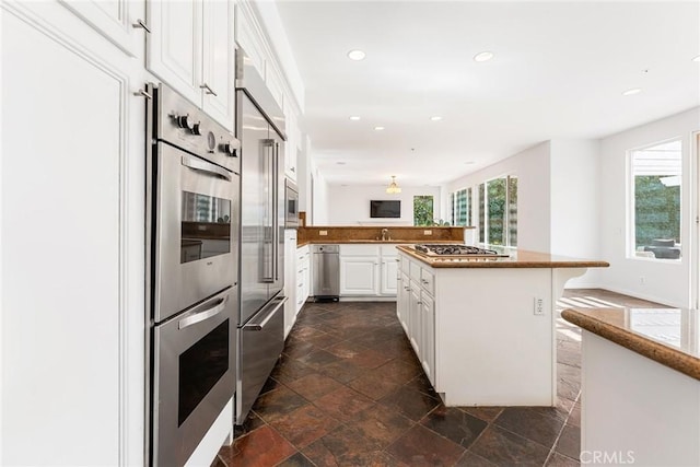 kitchen with a breakfast bar area, stainless steel appliances, a kitchen island, white cabinetry, and kitchen peninsula