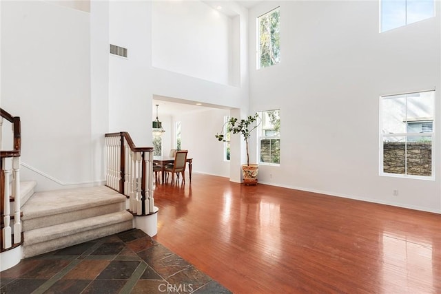 foyer with hardwood / wood-style flooring and a towering ceiling