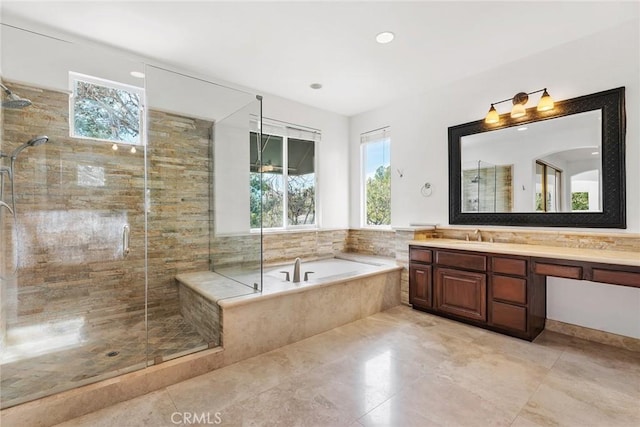 bathroom with plus walk in shower, vanity, and a wealth of natural light