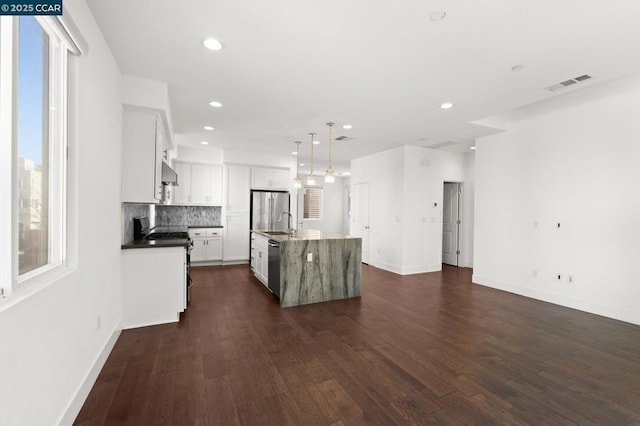 kitchen featuring appliances with stainless steel finishes, dark hardwood / wood-style flooring, pendant lighting, a kitchen island with sink, and white cabinets