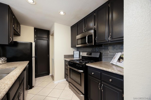 kitchen featuring stainless steel appliances, sink, light tile patterned floors, and backsplash